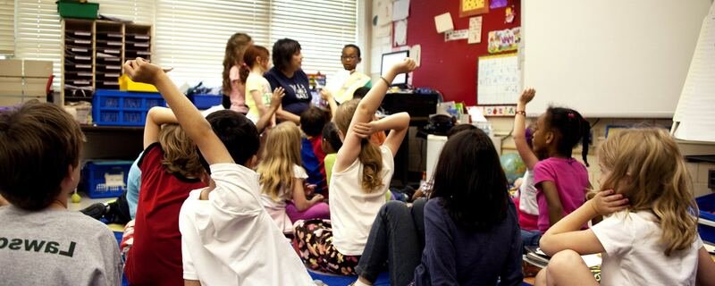 Students raising hands, engaged in classroom activity