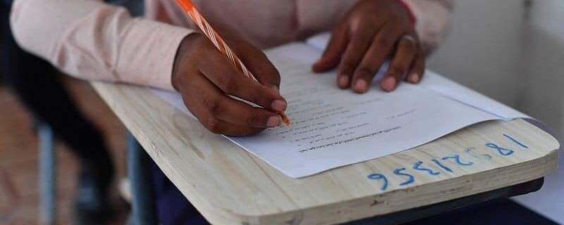 Student writing answers on an exam paper